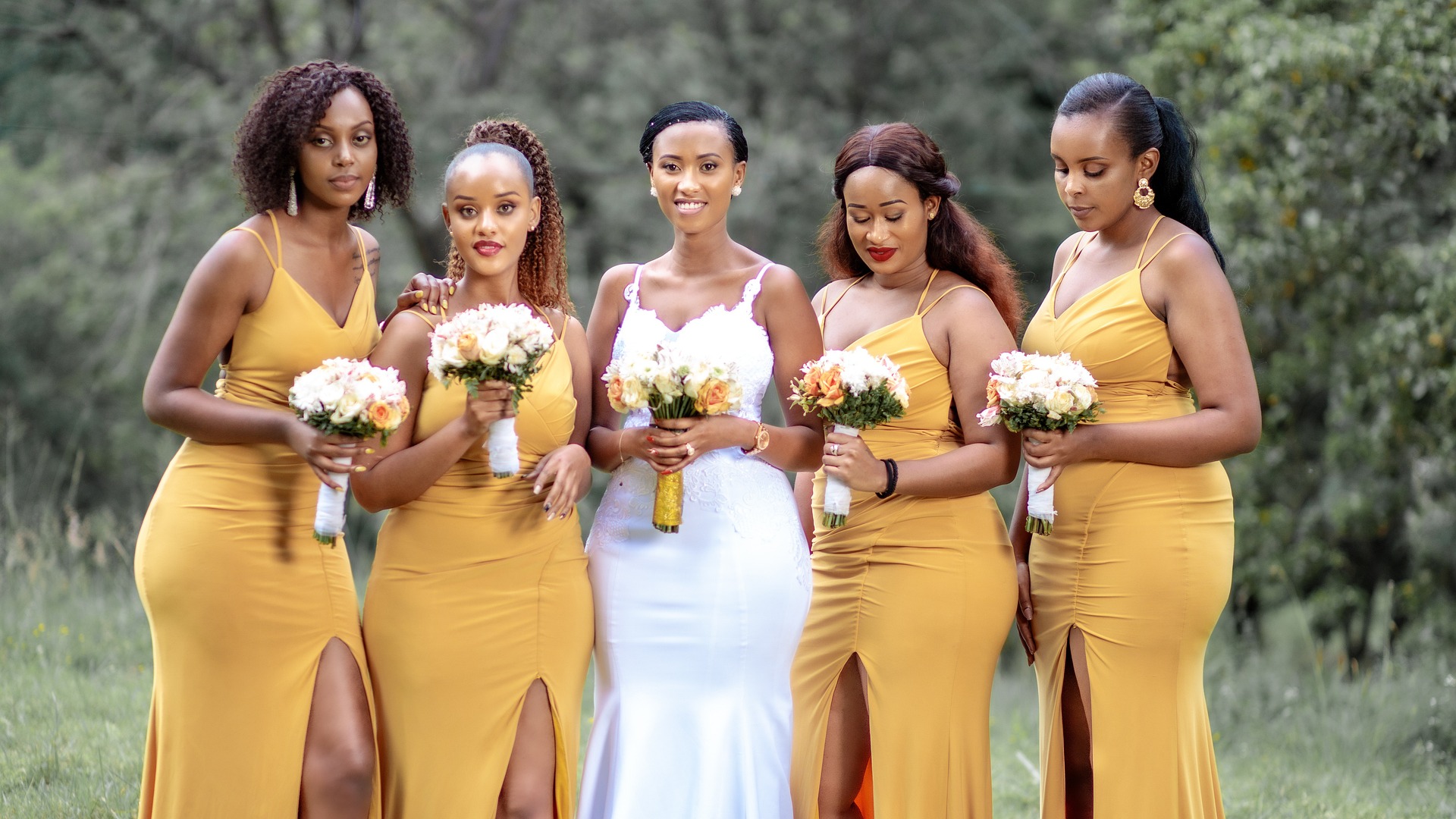 A bride and her bridesmaids in yellow, bouquets in hand