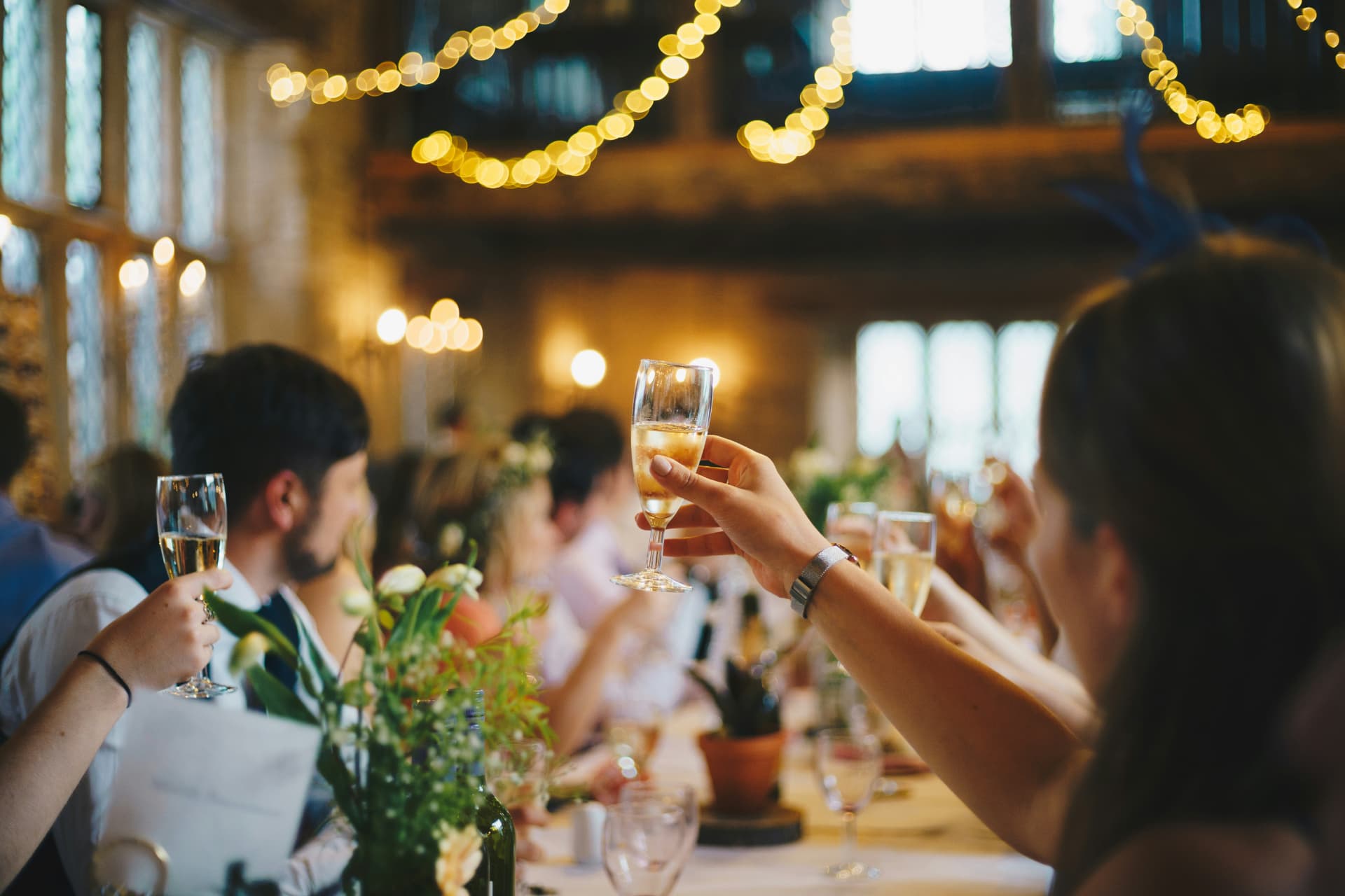 Guests raising a toast under warm string lights