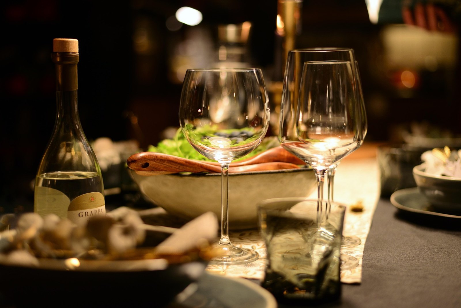 Candlelight on a long dinner table, glasses waiting for guests